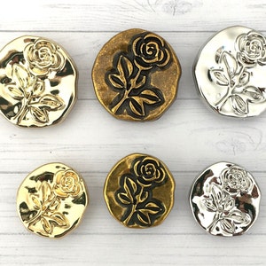 May include: Six decorative buttons with a rose design. The buttons are made of metal and have a gold or silver finish. The roses are embossed and have a three-dimensional effect.