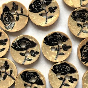 Puede incluir: Una colecci&oacute;n de 12 botones de madera con un dise&ntilde;o de rosa negra. Los botones son beige con una superficie ligeramente texturizada. Cada bot&oacute;n tiene dos agujeros.