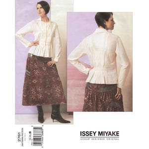 Pode incluir: Um padrão de costura original vintage da Vogue do designer Issey Miyake. O padrão apresenta uma blusa creme com pregas e uma saia longa com um padrão floral. A modelo está a usar botas pretas. O tamanho do padrão é 14, 16, 18.