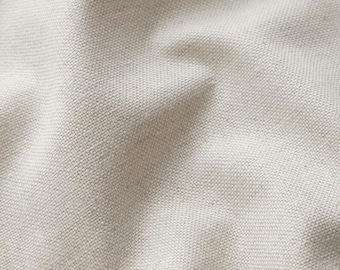 May include: Close-up of a textured, off-white fabric. The material has a woven appearance with a subtle pattern of small, evenly spaced squares. The fabric is slightly creased, creating shadows and variations in tone.