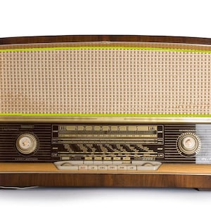 Puede incluir: Radio de madera vintage con una cubierta de altavoz de color beige claro y un marco de madera oscura. La radio presenta un dial de sintonizaci&oacute;n, botones y una rejilla de altavoz. Un equipo de audio cl&aacute;sico.
