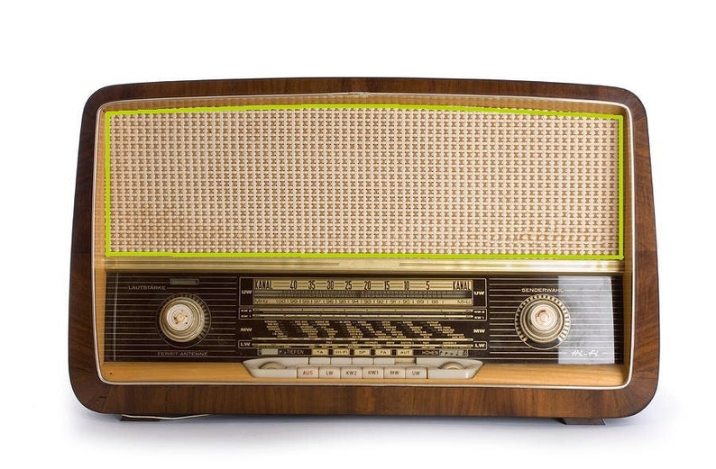 Puede incluir: Radio de madera vintage con una cubierta de altavoz de color beige claro y un marco de madera oscura. La radio presenta un dial de sintonizaci&oacute;n, botones y una rejilla de altavoz. Un equipo de audio cl&aacute;sico.