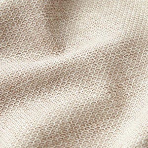 Può includere: Primo piano di un tessuto a trama fitta con un motivo a nido d'ape strutturato. Il tessuto è di un colore beige neutro, con sottili variazioni di tono, creando un senso di profondità e dimensione. La trama è fitta e sembra resistente.