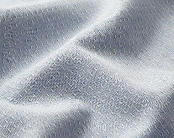 May include: Close-up of a light blue fabric with a subtle white diamond pattern. The fabric has a textured, woven appearance.