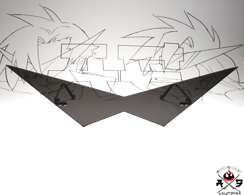 Puede incluir: Una forma geom&eacute;trica negra angular, que se asemeja a un par de gafas de sol, con dos peque&ntilde;os objetos circulares negros unidos a la parte superior de cada brazo. La forma se coloca frente a un fondo blanco con un dibujo de l&iacute;nea en blanco y negro de dos personajes de anime.