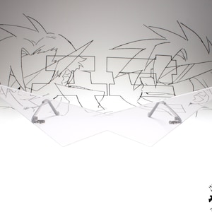 Puede incluir: Una visera de pl&aacute;stico transparente con dos soportes de metal plateado. La visera tiene forma de alas. La visera est&aacute; delante de un fondo blanco con un dibujo en blanco y negro de dos personajes de anime.