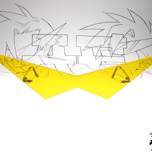 Puede incluir: Gafas de pl&aacute;stico amarillo en forma de rayo con dos bisagras met&aacute;licas. Las gafas est&aacute;n sobre un fondo blanco con un dibujo en blanco y negro de dos personajes de anime.