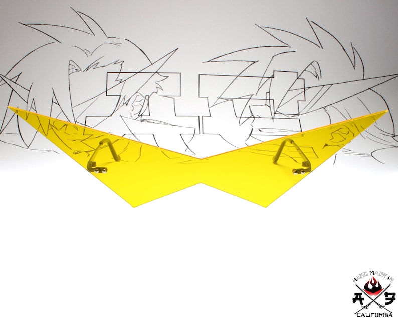 Puede incluir: Gafas de pl&aacute;stico amarillo en forma de rayo con dos bisagras met&aacute;licas. Las gafas est&aacute;n sobre un fondo blanco con un dibujo en blanco y negro de dos personajes de anime.
