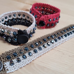 May include: Three crocheted bracelets with black, white, and brown thread and iridescent beads. Each bracelet has a button closure.