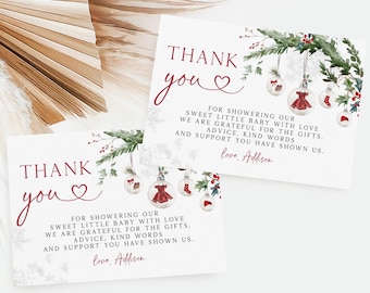 Könnte beinhalten: Zwei weiße Karten mit dem Schriftzug "Thank You" in burgunderfarbener Schrift, mit einem Herzsymbol. Die Karten haben ein Weihnachtsthema mit Illustrationen von Kugeln, einem Kleid und einem Weihnachtsmannhut. Der Text lautet "Für das Überhäufen unseres kleinen Babys mit Liebe..."