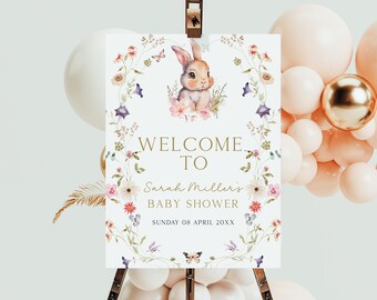Könnte beinhalten: Willkommensschild für eine Babyparty mit einer Aquarellillustration eines Hasen und eines Blumenkranzes. Auf dem Schild steht "WELCOME TO Sarah Miller's BABY SHOWER" mit dem Datum. Das Schild wird auf einer Staffelei angezeigt.