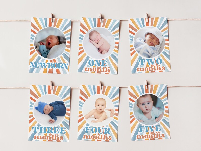 May include: A set of six baby milestone cards, each featuring a photo of a baby and the month. The cards are decorated with a retro sunburst design in orange, blue, and white, and are clipped to a string.