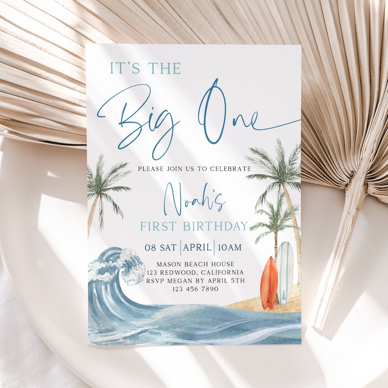 May include: A blue and white beach-themed first birthday invitation for a boy named Noah. The invitation features a watercolor illustration of ocean waves, palm trees, and surfboards. The text reads "It's the Big One, Please join us to celebrate Noah's First Birthday, 08 Sat April 10am, Mason Beach House, 123 Redwood, California, RSVP Megan by April 5th, 123 456 7890."