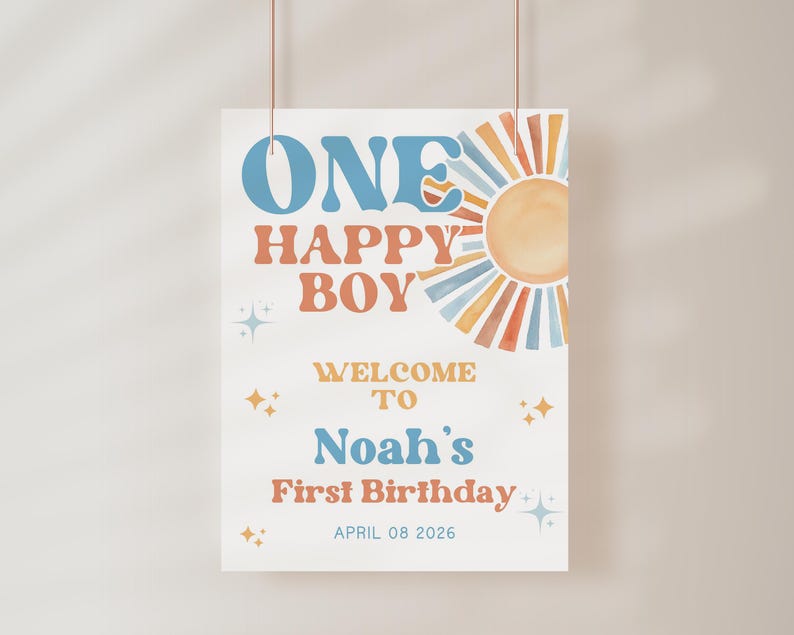 May include: A rectangular sign with the text "ONE HAPPY BOY" in blue and orange, with a watercolor sun illustration. The sign reads "WELCOME TO Noah's First Birthday" and the date "APRIL 08 2026".