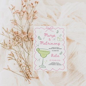 Puede incluir: Una tarjeta de invitaci&oacute;n rosa y blanca con una ilustraci&oacute;n de margarita y el texto "Margs & Matrimony Join us for a Bachelorette Weekend Celebrating Katie 08-10 July 2026 Aspen Villa Highlands Estate Scottsdale, Arizona"