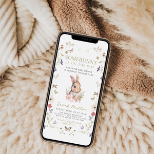 Puede incluir: Una invitaci&oacute;n digital para un baby shower con un borde floral y una linda ilustraci&oacute;n de un conejito. El texto dice "Somebunny is on the way" e incluye el nombre "Sarah Miller" y los detalles del evento.