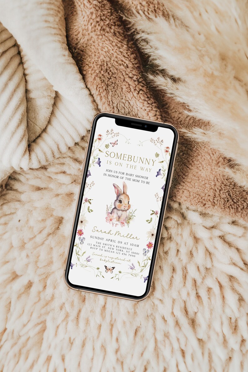 Puede incluir: Una invitaci&oacute;n digital para un baby shower con un borde floral y una linda ilustraci&oacute;n de un conejito. El texto dice "Somebunny is on the way" e incluye el nombre "Sarah Miller" y los detalles del evento.
