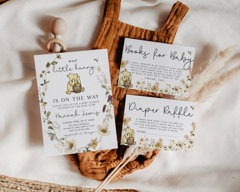 May include: A Winnie the Pooh themed baby shower invitation with a floral wreath and the text "our little hunny is on the way". The invitation includes details for the shower, including the date, time, location, and RSVP information. There are also two cards for guests to bring books or participate in a diaper raffle.