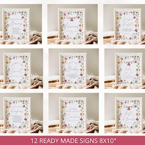 May include: A collection of nine rectangular signs in white textured frames, each featuring a colorful floral border and printed text for baby shower activities. The signs include titles like Message from the Bump, Diaper Raffle, and Guess How Many Candies, measuring 8 by 10 inches.