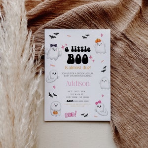 May include: A white baby shower invitation with a Halloween theme. The invitation features a cartoon ghost with the text "a little BOO is almost due!" and the name "Addison". The invitation also includes the date, time, and location of the baby shower.