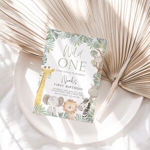 May include: A green and white jungle-themed first birthday party invitation with the text "Wild One" and "Noah's First Birthday". The invitation features a giraffe, elephant, lion, zebra, and other jungle animals.