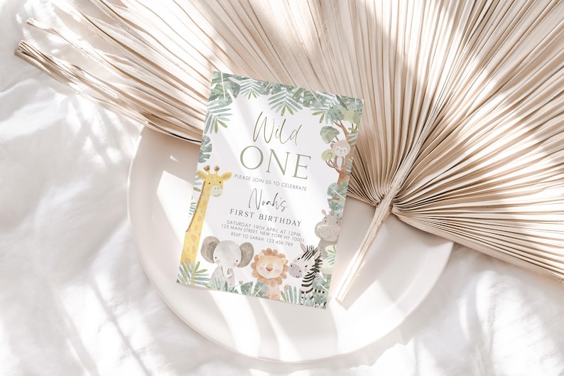 May include: A green and white jungle-themed first birthday party invitation with the text "Wild One" and "Noah's First Birthday". The invitation features a giraffe, elephant, lion, zebra, and other jungle animals.