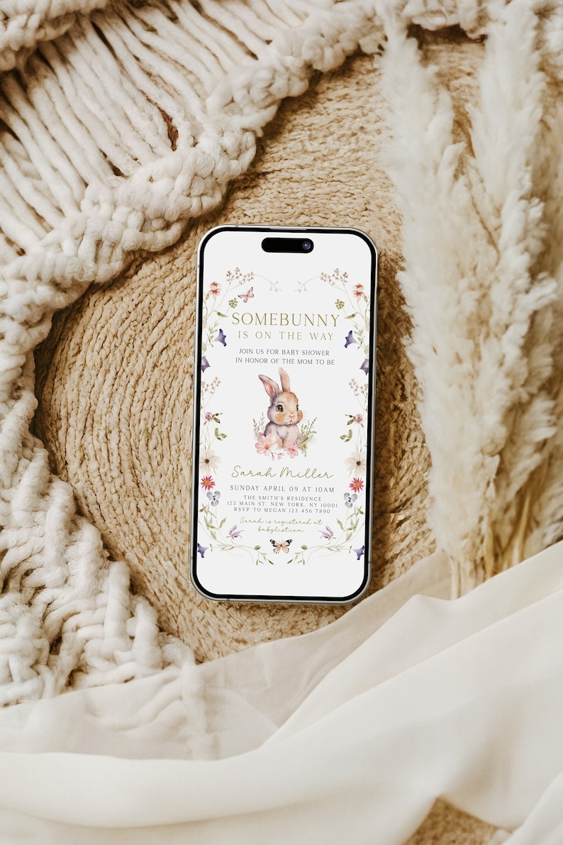 Puede incluir: Una invitaci&oacute;n digital para un baby shower con un borde floral y una linda ilustraci&oacute;n de un conejito. El texto dice "Somebunny is on the way" e incluye la fecha, la hora y la ubicaci&oacute;n del evento. Tambi&eacute;n se incluye informaci&oacute;n de RSVP.