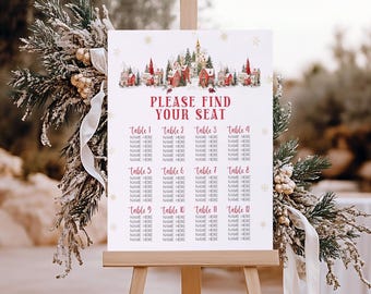 May include: A white sign on a wooden easel with the text "PLEASE FIND YOUR SEAT" in red. The sign has a watercolor illustration of a winter village and snowflakes. Below are table numbers and spaces for names.