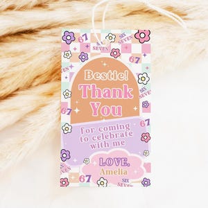 May include: A rectangular gift tag with a retro design. The tag features the words "Bestie! Thank You" in pink and orange, with the text "for coming to celebrate with me" below. The tag is decorated with flowers and the number "67".