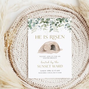 May include: A white card with green watercolor leaves and a gold inscription that reads "He is Risen". The card also features a brown illustration of a tomb with a rolling stone. The text below the illustration reads "Please join us for an Easter Brunch hosted by the Sunset Ward Sunday April 02 at 8am Please bring a special dish to share."