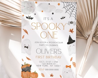 May include: A white invitation card with a gold and black Halloween theme. It says "It's a Spooky One" and "Oliver's First Birthday". The card features a ghost, a spider, a bat, and a pumpkin.