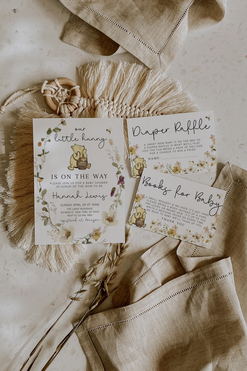 May include: A Winnie the Pooh themed baby shower invitation with floral accents. The invitation includes the text "our little hunny is on the way".