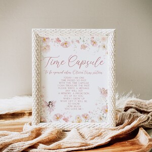May include: A white frame with a floral design and the text "Time Capsule to be opened when Oliwia turns sixteen." The text inside the frame reads: "Today I am one. Time passes so fast. With this time capsule I can treasure the past. Please write a message. Any will do. A memory, a prediction. It's up to you. When I grow up what gift it will be. To know how much you love me!"