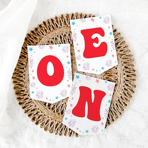 May include: A set of three white paper pennants with red letters spelling "ONE" and a blue and red firework design.