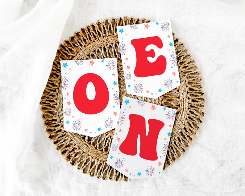 May include: A set of three white paper pennants with red letters spelling "ONE" and a blue and red firework design.