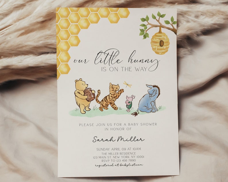 May include: A Winnie the Pooh themed baby shower invitation featuring a yellow honeycomb pattern, a beehive, and illustrations of Winnie the Pooh, Tigger, Piglet, and Eeyore. The text reads "our little hunny is on the way".