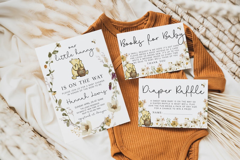 May include: A Winnie the Pooh themed baby shower invitation with floral accents. The invitation reads "our little hunny is on the way" and includes the date, time, and location of the shower. There are also two cards for guests to write messages for the baby, one for books and one for diapers.