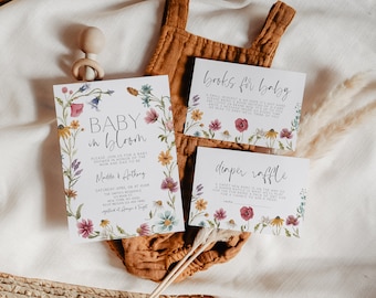 May include: Baby shower stationery set featuring a floral design. The invitation card says "Baby in Bloom" with event details. Accompanying cards request books and a diaper raffle. The cards are adorned with watercolour flowers.
