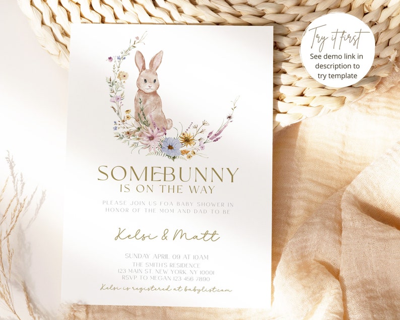 May include: A baby shower invitation featuring a watercolour illustration of a bunny rabbit sitting on a crescent moon surrounded by flowers. The text reads "Somebunny is on the way" and includes the names Kelsi & Matt, the date and time of the shower, and the address.