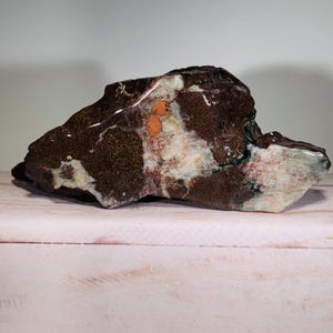 May include: A large, irregularly shaped rock with a brown, white, and orange mottled pattern. The rock has a smooth, polished surface.