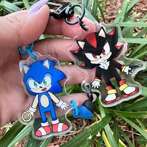 May include: A blue and red Sonic the Hedgehog character keychain and a black and red Shadow the Hedgehog character keychain connected by a blue and black chain.