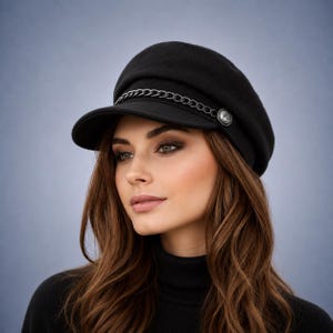May include: A black newsboy cap featuring a structured crown and a short, stiff brim. A thin, dark metal chain is attached across the front of the cap, secured on each side by a small, round, metallic button detail with an embossed design.