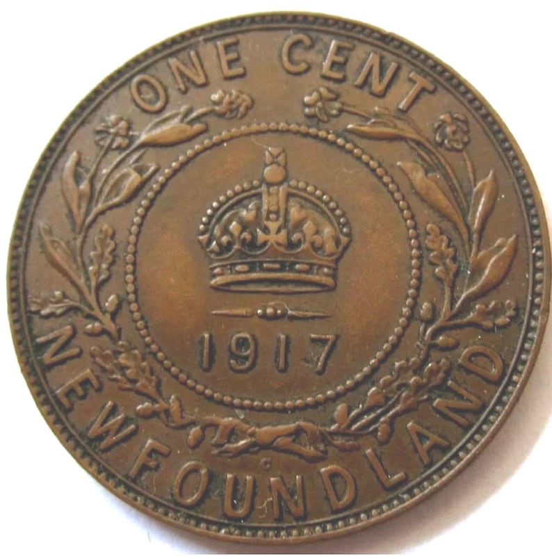 May include: A copper-colored Newfoundland one-cent coin from 1917. The coin features a crown, floral designs, and the text "ONE CENT" and "NEWFOUNDLAND". The coin is round with a detailed design.