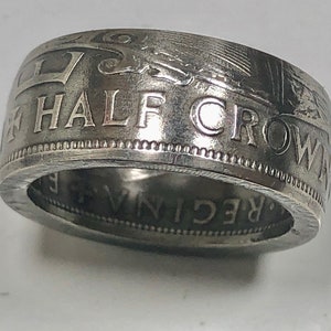 May include: A silver ring made from a half crown coin. The coin features the inscription "HALF CROWN" and a design of a crown.