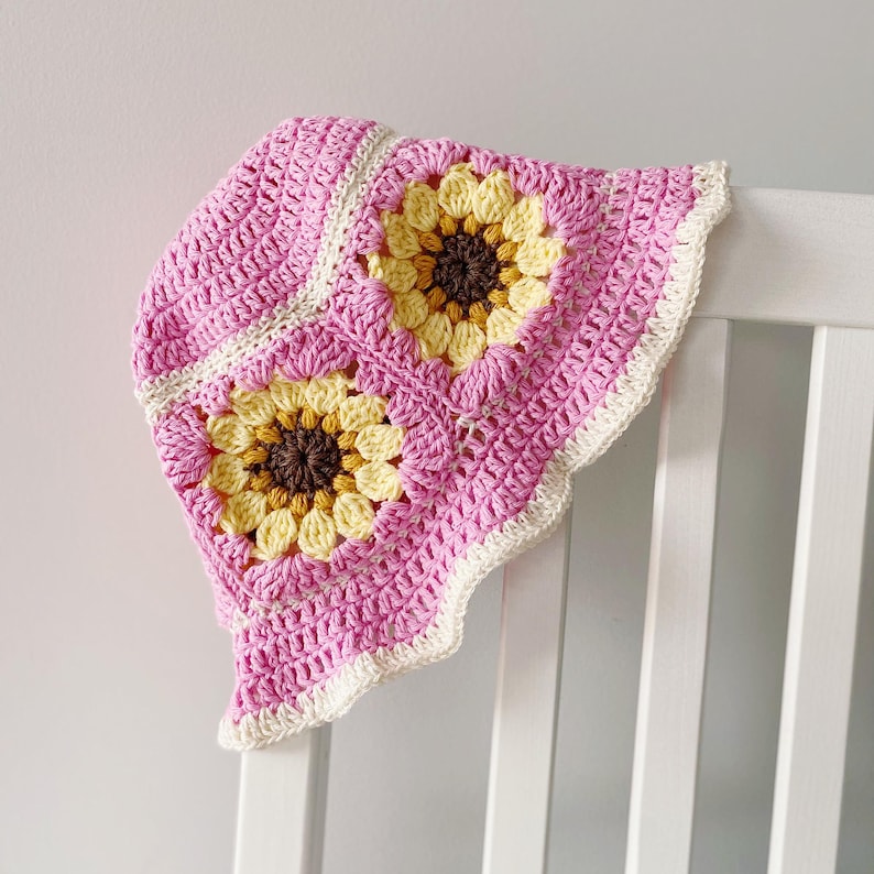 Baby pink crochet sunflower bucket hat with white edging and sunflowers around the middle of the hat.