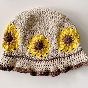 Close up of beige crochet sunflower bucket hat with dark brown edging and sunflowers around the middle of the hat.