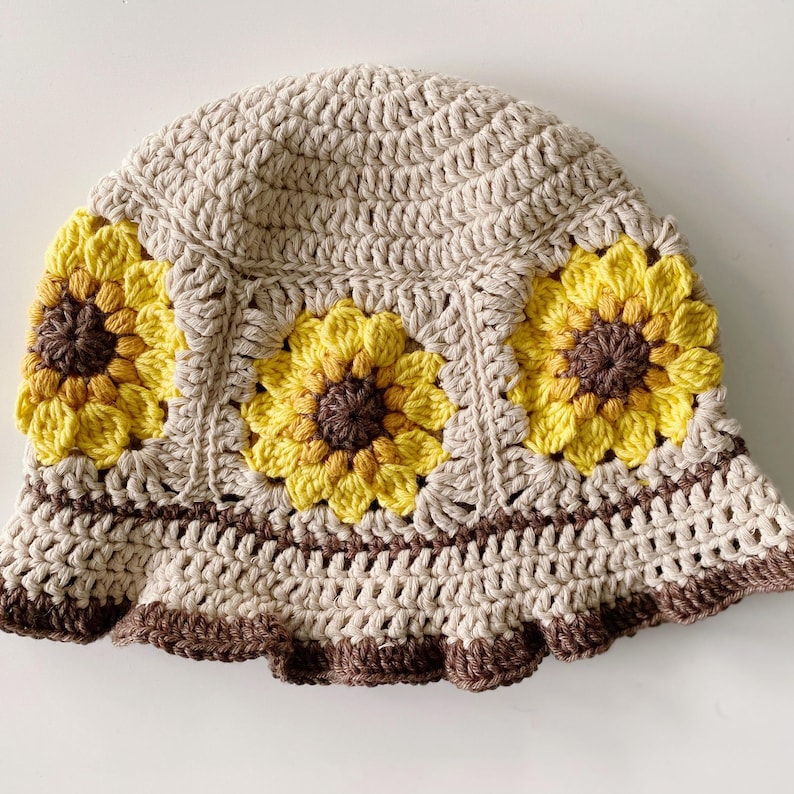 Close up of beige crochet sunflower bucket hat with dark brown edging and sunflowers around the middle of the hat.