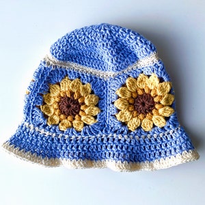 Pale blue crochet sunflower bucket hat with white edging and sunflowers around the middle of the hat.