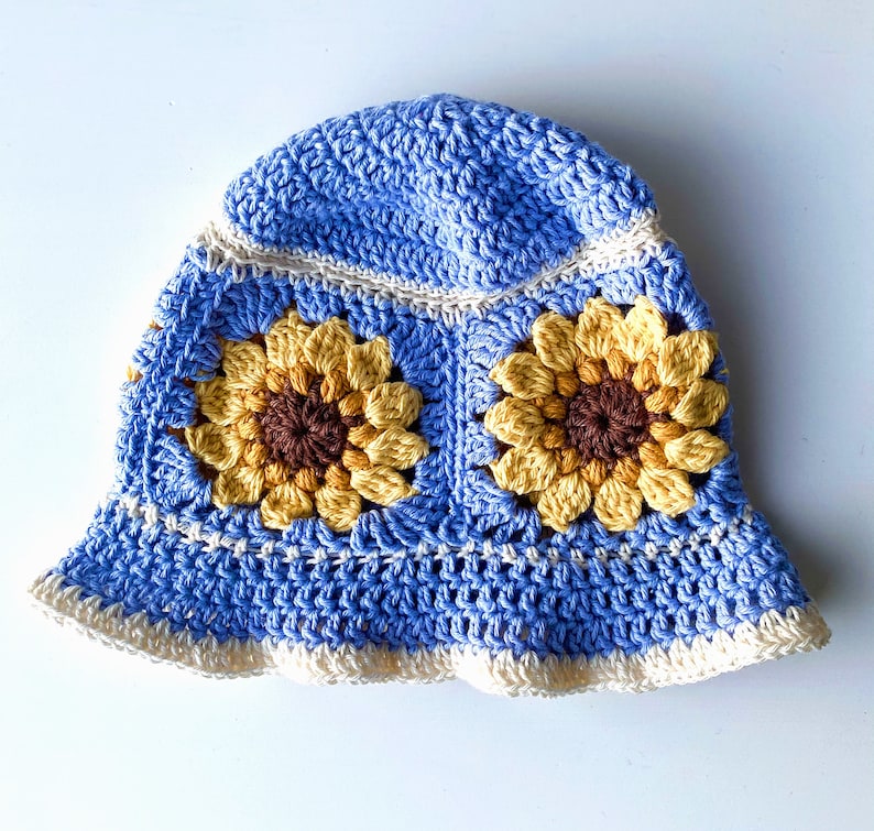 Pale blue crochet sunflower bucket hat with white edging and sunflowers around the middle of the hat.