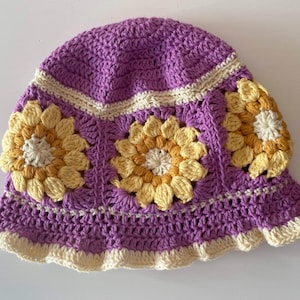 Close up of mauve crochet sunflower bucket hat with cream edging and sunflowers around the middle of the hat.
